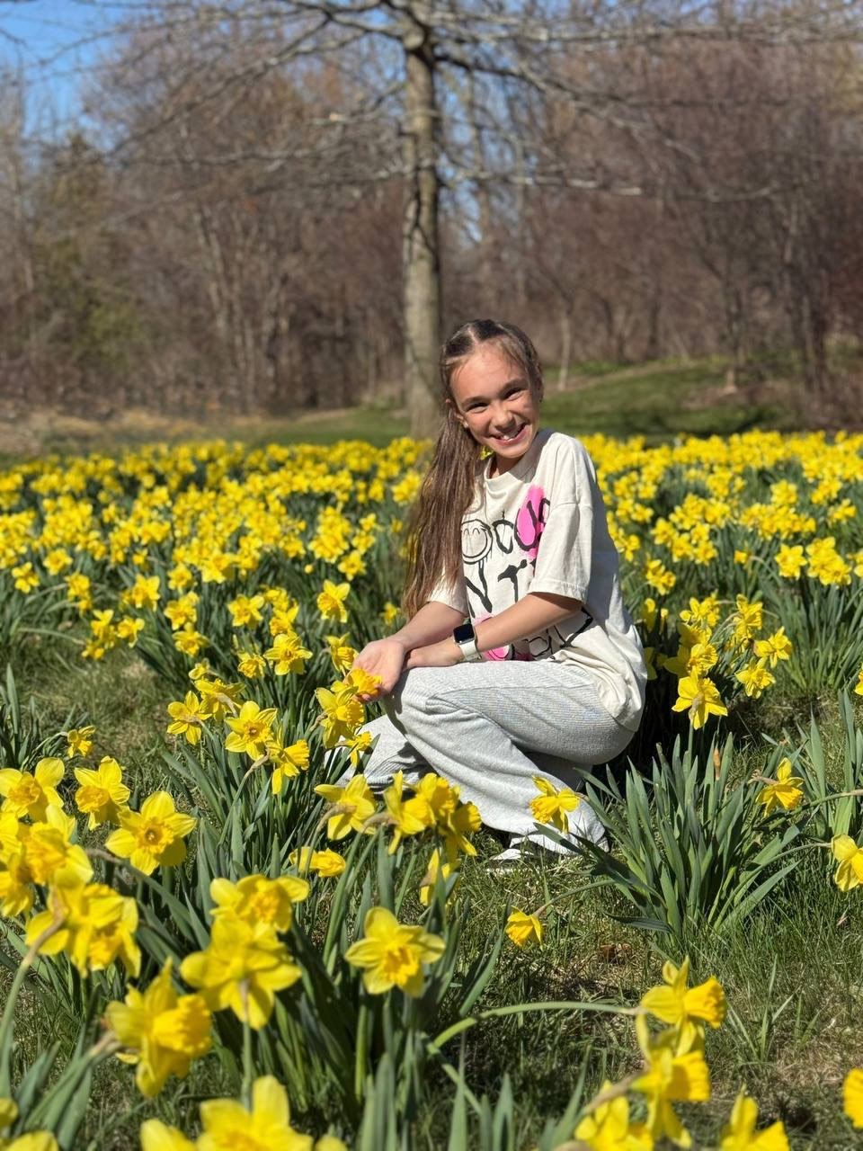 Anna smiling in a field of yellow flowers